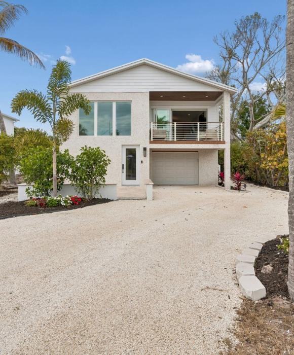 Coastal Home Exterior Daytime Front Facade White Stucco Gravel Driveway Palm Trees