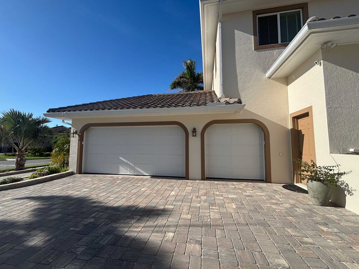 Finished custom home garage exterior with dual white doors by Adkins Building & Construction in Bradenton, FL.