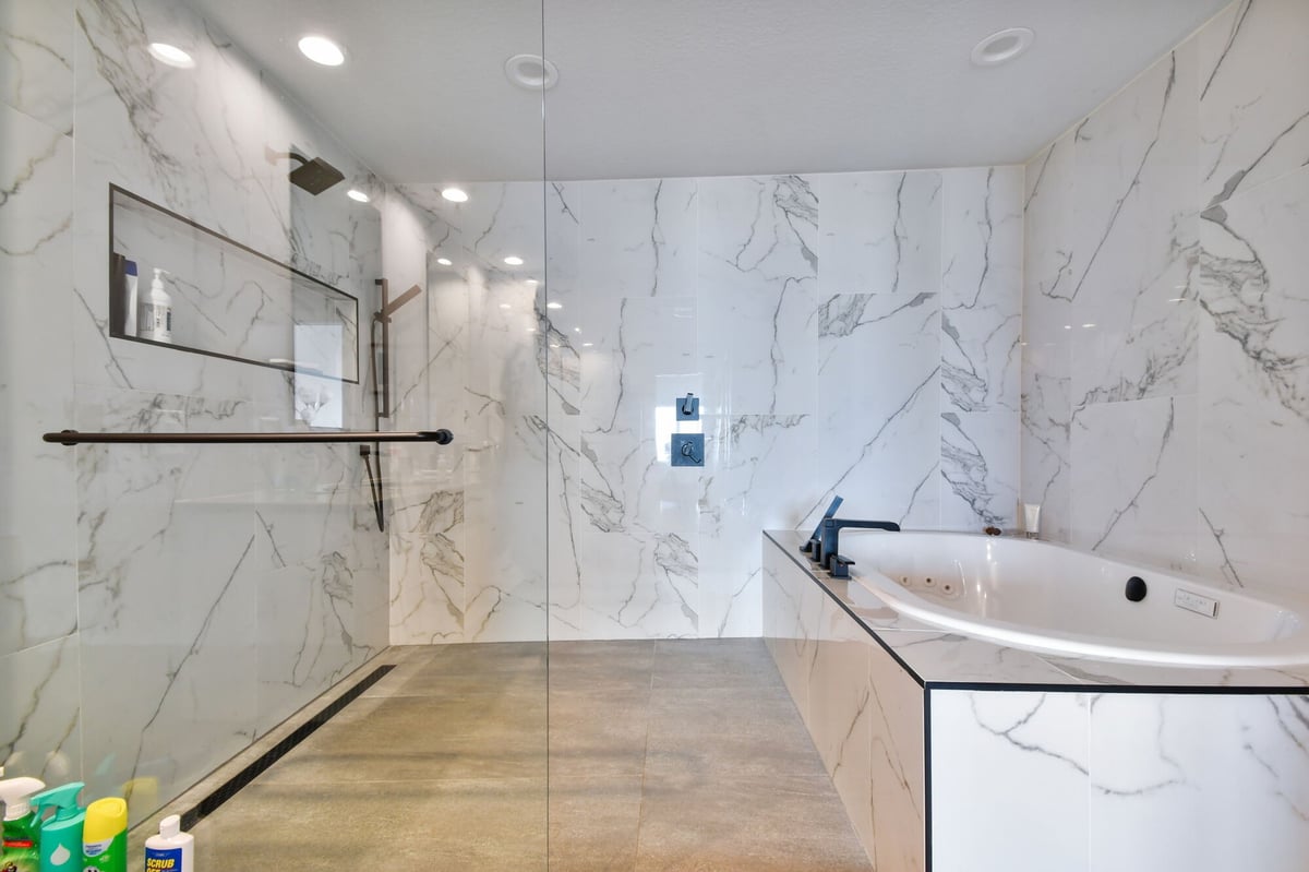 Luxury custom bathroom with marble tile, walk-in shower, and soaking tub in Bradenton, FL by Adkins Building & Construction.