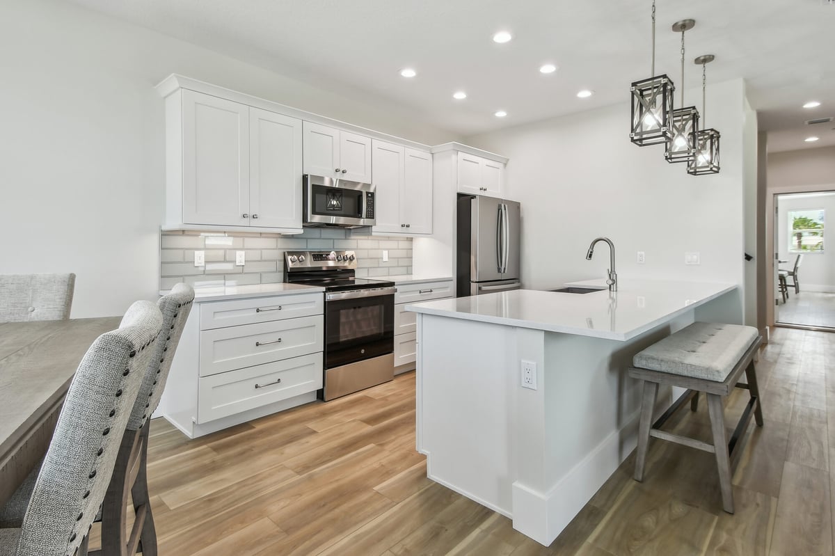 Modern white kitchen with island in a Bradenton, FL custom home by Adkins Building & Construction
