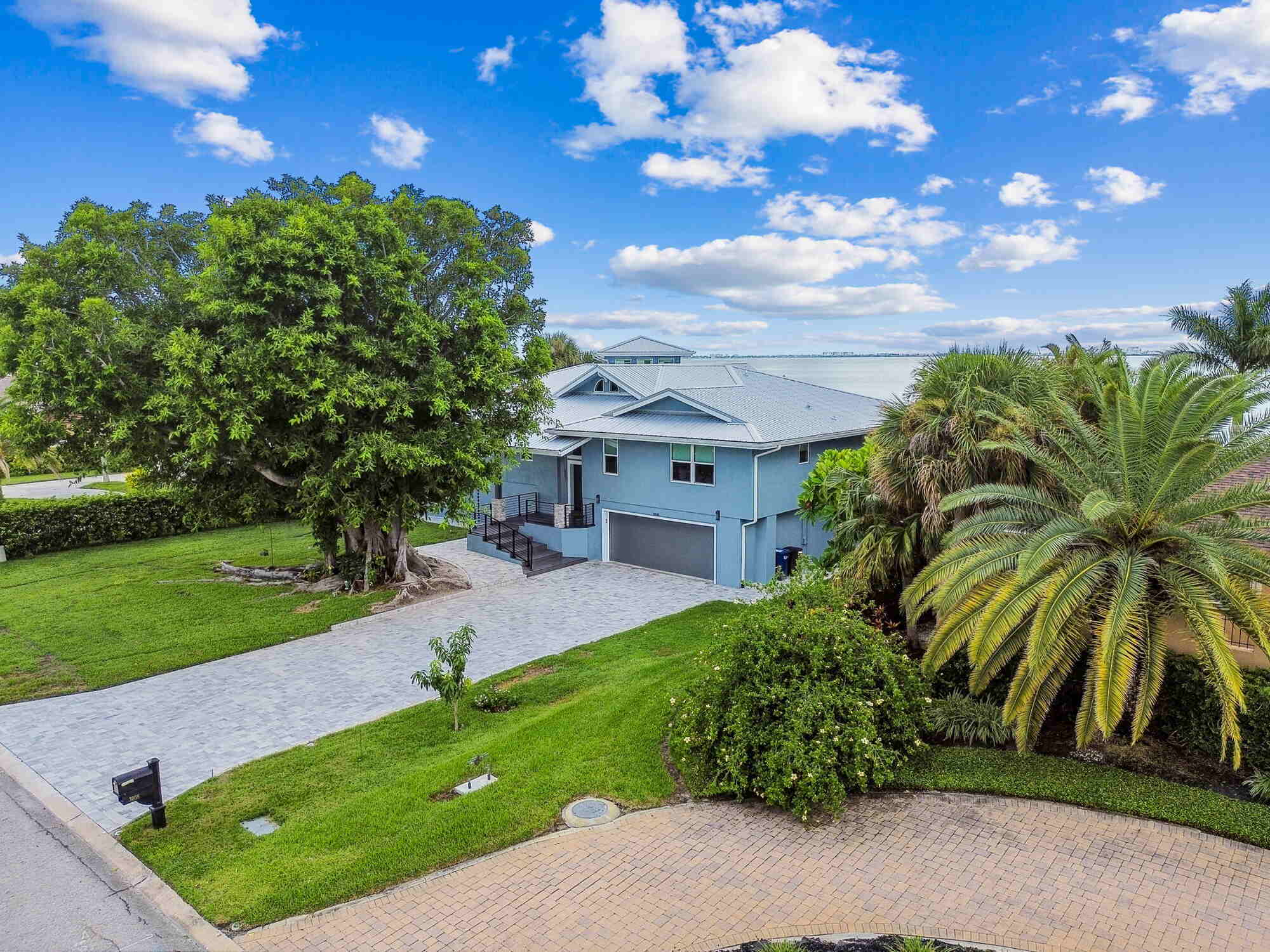 Street view of custom coastal home with tropical landscaping in Bradenton, FL by Adkins Building & Construction.