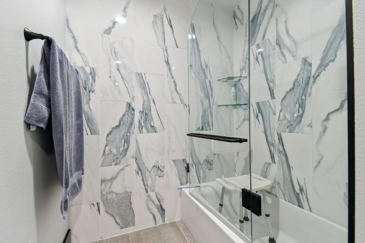 Accessible custom shower featuring sleek glass doors and modern marble wall tiles in Bradenton, FL home remodel.
