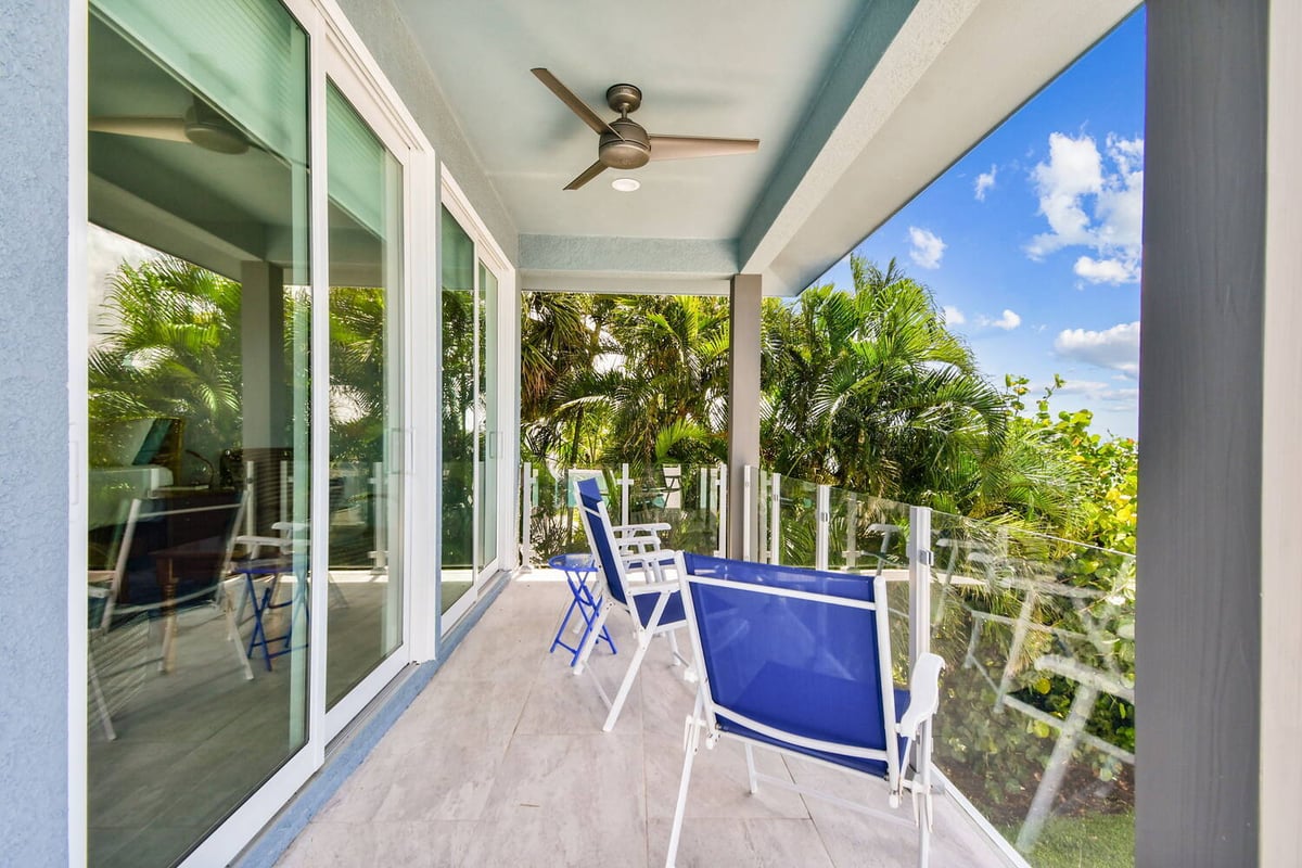 Covered patio with ceiling fan and glass railing in Bradenton home by Adkins Building & Construction.