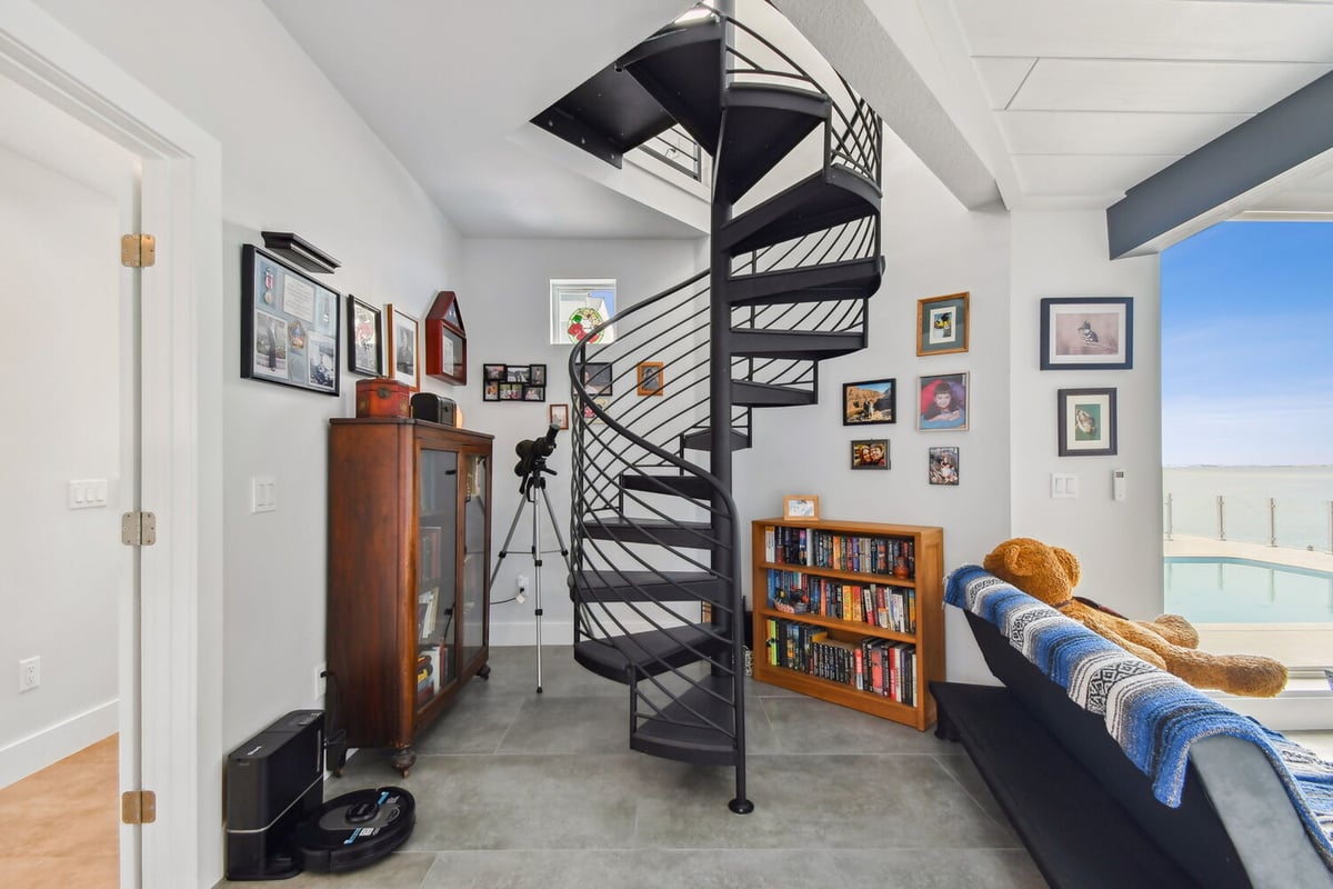Cozy reading nook with black spiral staircase and lake views in Bradenton custom home by Adkins Building & Construction.