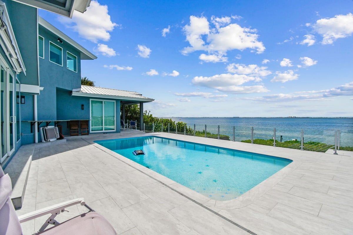 Expansive pool deck overlooking the ocean with glass railing in Bradenton, FL custom home by Adkins Building & Construction.