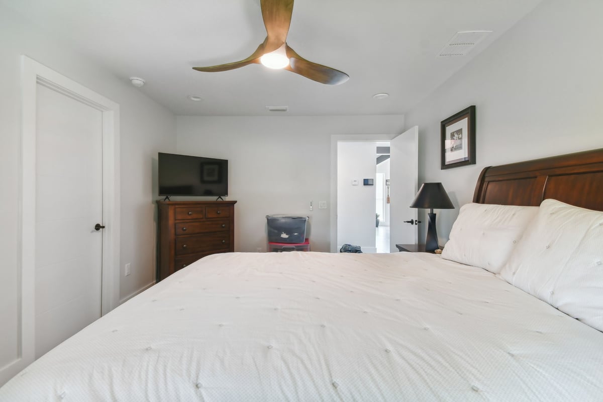 Minimalist bedroom remodel with dark wood furniture and modern fan by Adkins Building & Construction in Bradenton, FL.
