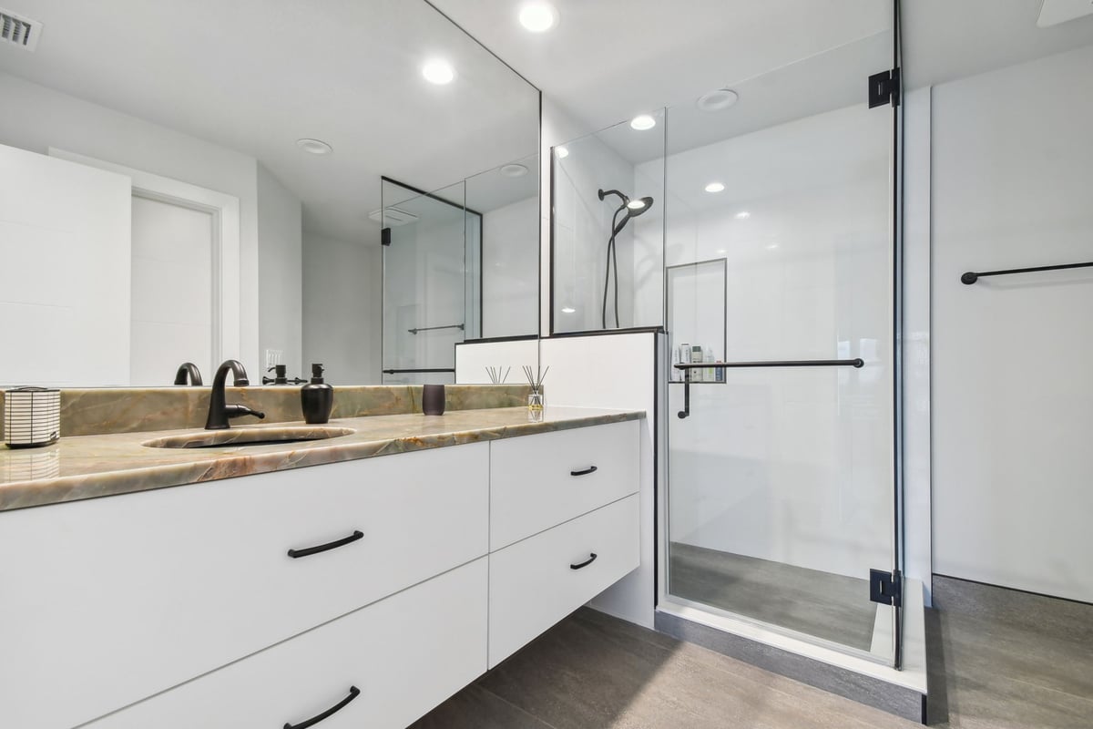 Modern bathroom renovation with glass walk-in shower and stone countertop in Bradenton, FL by Adkins Building & Construction.