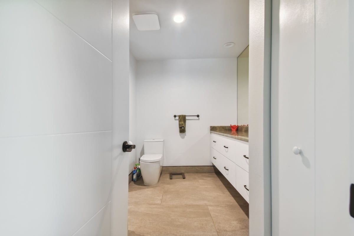 Modern bathroom with floating vanity and neutral tile by Adkins Building & Construction in Bradenton, FL.