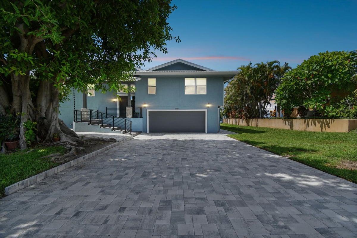 Newly completed custom home exterior with modern blue finish and paver driveway by Adkins Building & Construction in Bradenton, FL - 1