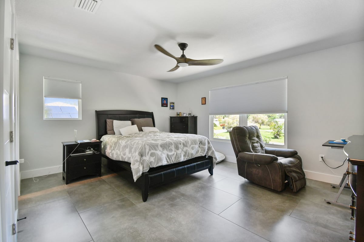 Spacious master bedroom with large windows and tile flooring in custom Bradenton home by Adkins Building & Construction.