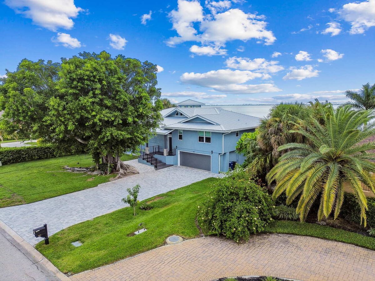 Street view of custom coastal home with tropical landscaping in Bradenton, FL by Adkins Building & Construction.