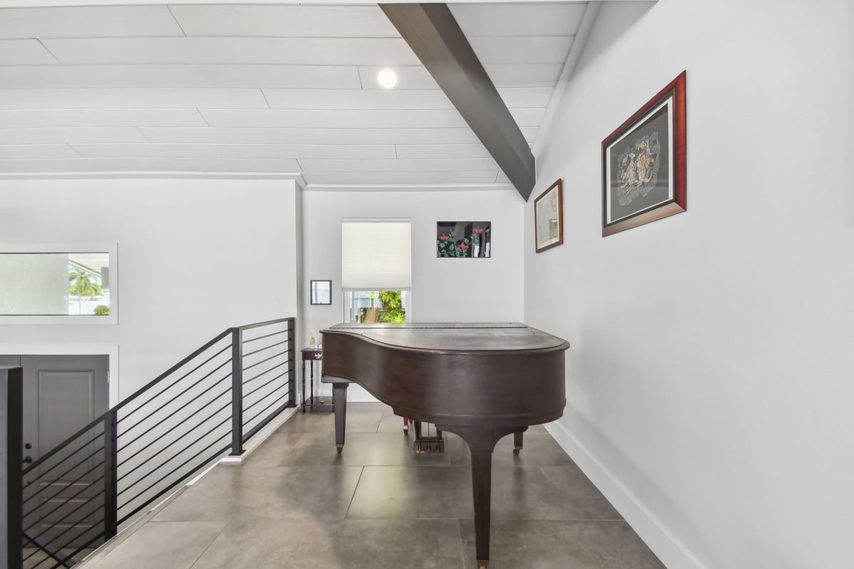 Upstairs loft area with grand piano and gallery wall in Bradenton custom home by Adkins Building & Construction.