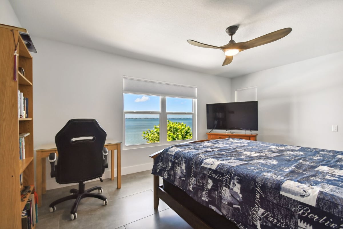 Waterfront bedroom with built-in desk and scenic view in a Bradenton, FL custom home by Adkins Building & Construction.