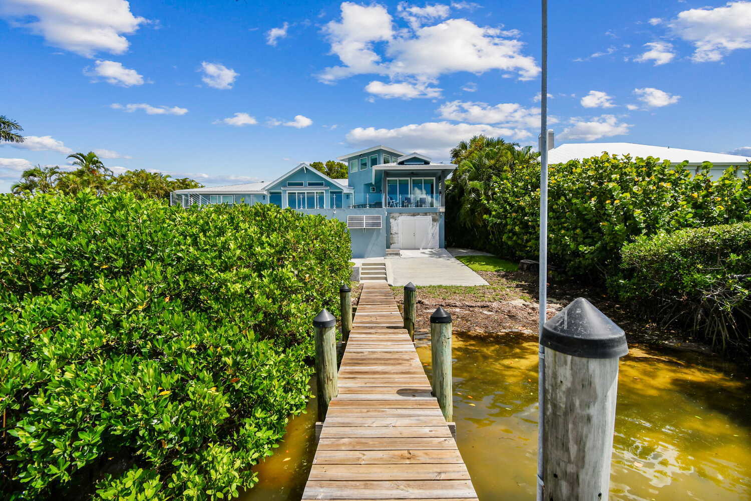 Waterfront dock view of modern coastal home in Bradenton, FL by Adkins Building & Construction.