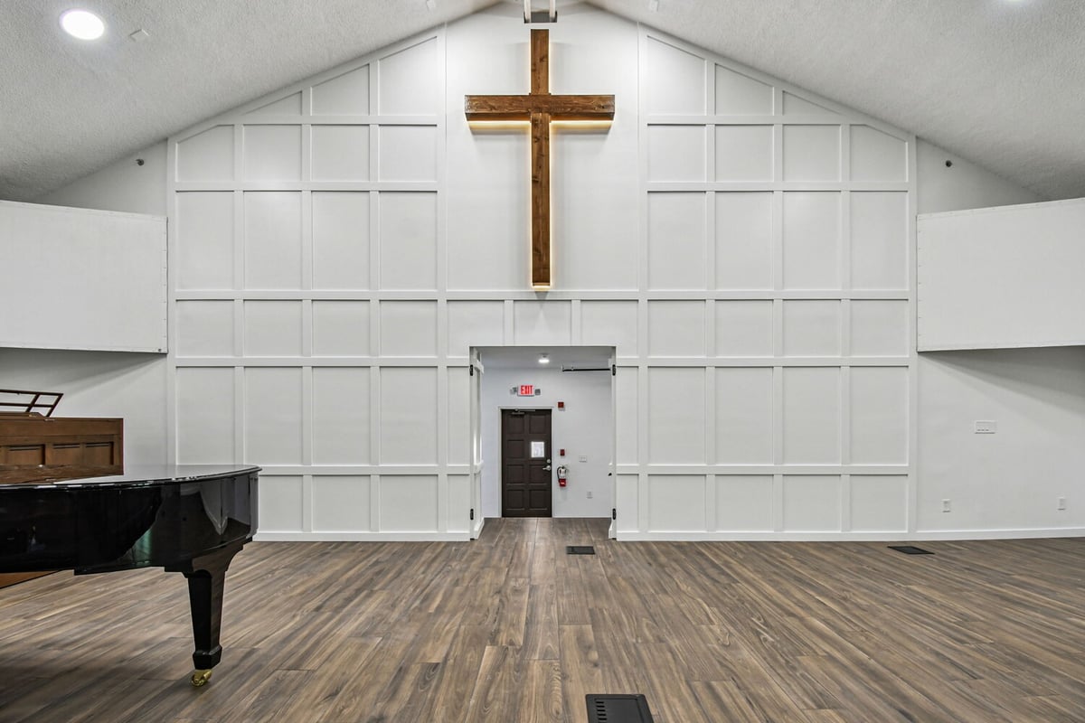 Interior view of stage entrance with wood flooring and illuminated cross by Adkins Building & Construction in Anna Maria, FL