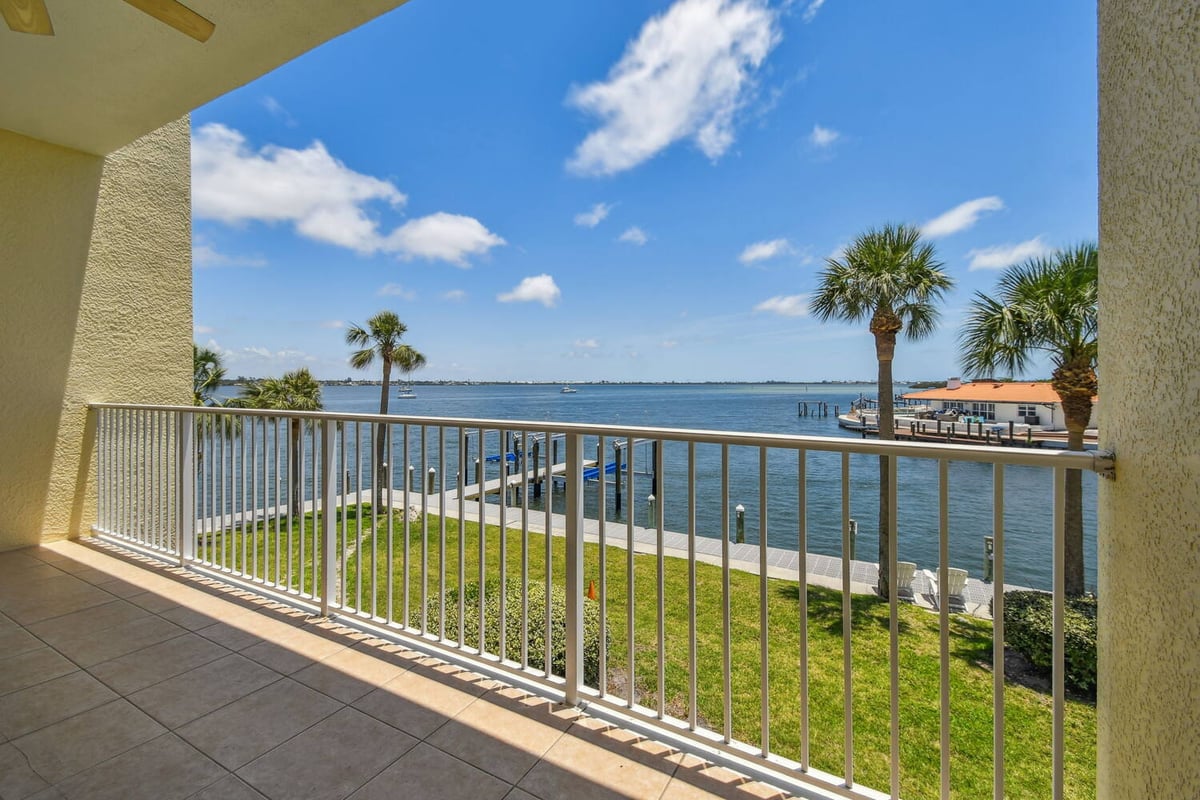 Angled balcony view of palm-lined shoreline and water in a Bradenton, FL custom home by Adkins Building & Construction.