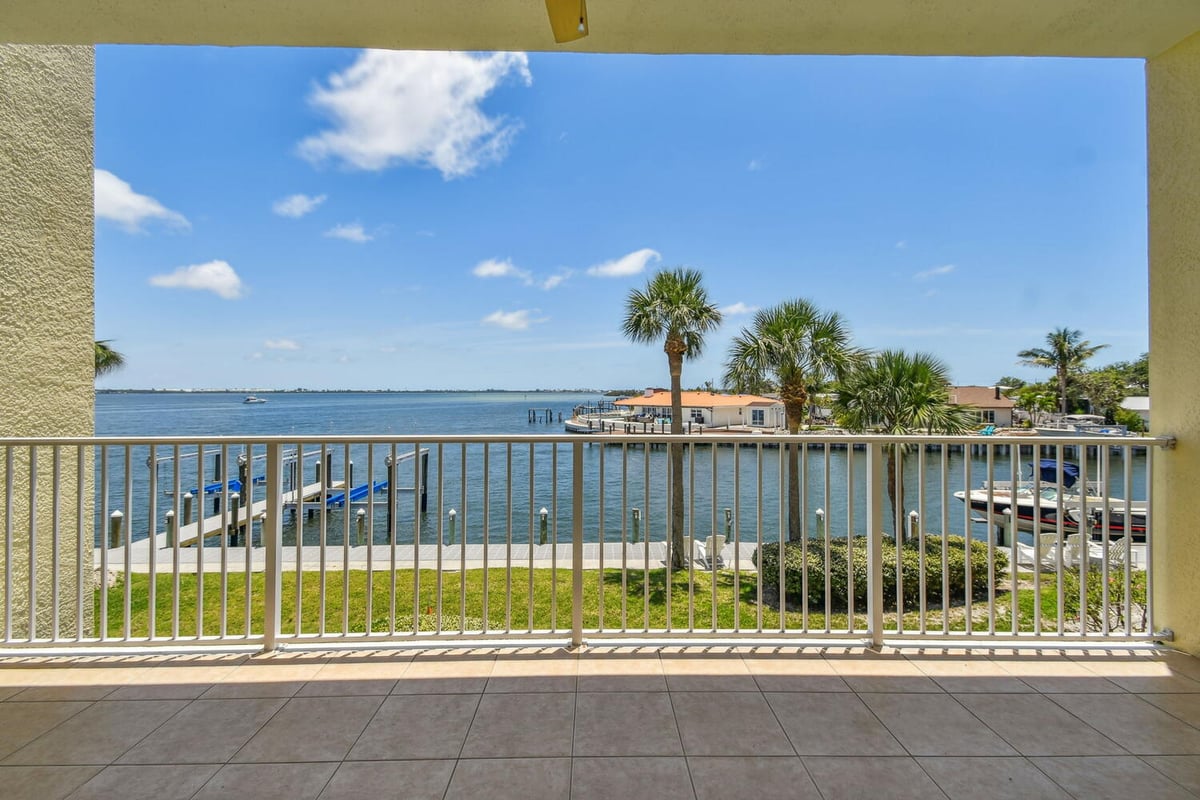 Covered balcony overlooking water and palm trees in a Bradenton custom home by Adkins Building & Construction.