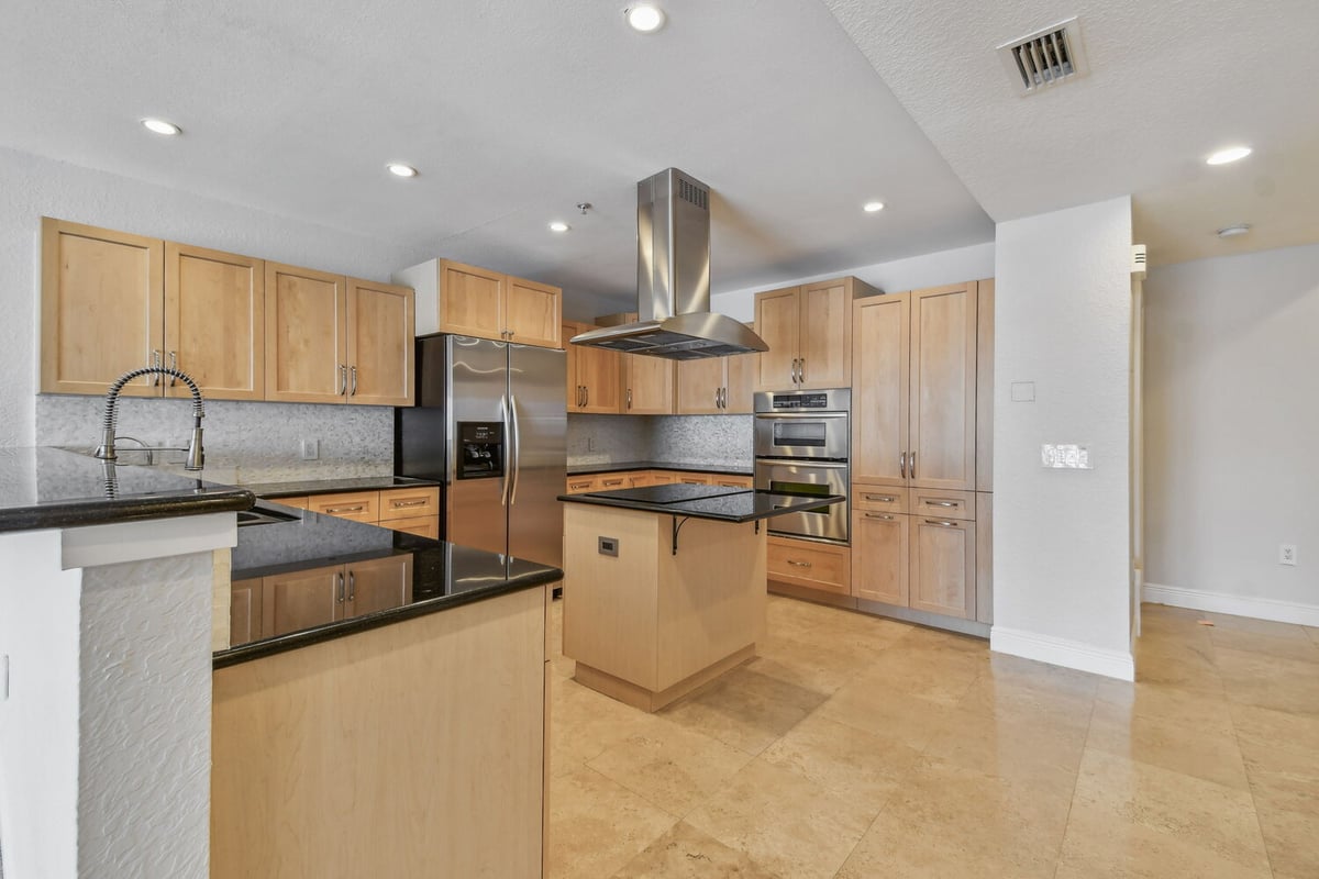 Open-concept kitchen featuring natural wood cabinetry in a Bradenton, FL custom home by Adkins Building & Construction.