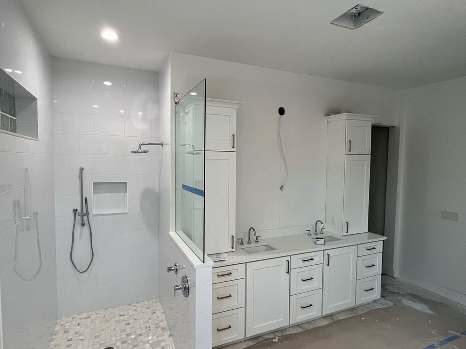 Custom white bathroom with dual vanity and glass shower under construction in Bayshore Gardens, FL