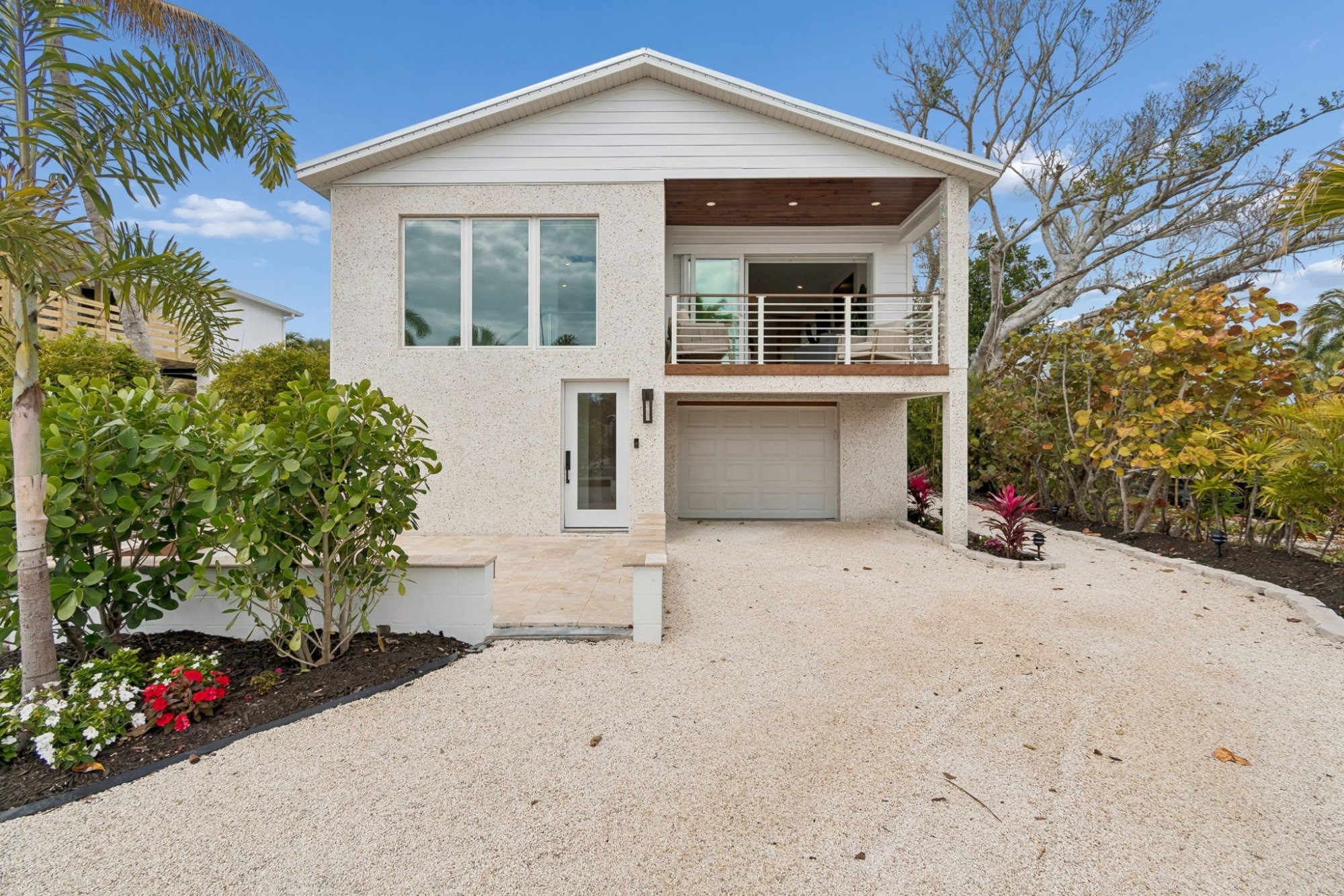 Coastal_Home_Exterior_Front_Entrance_White_Stucco_Garage_Upper_Balcony_Blue_Sky
