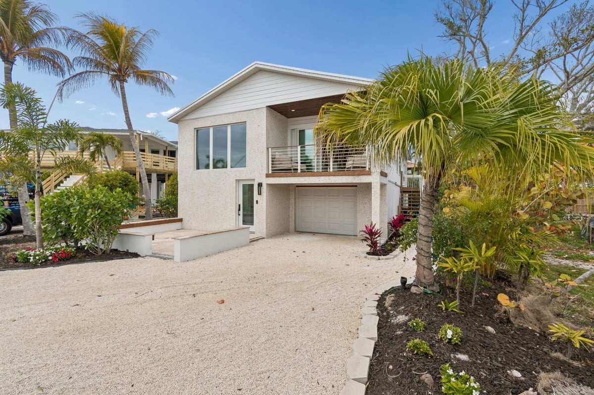 Coastal Home Exterior Front View White Stucco Upper Balcony Tropical Landscaping