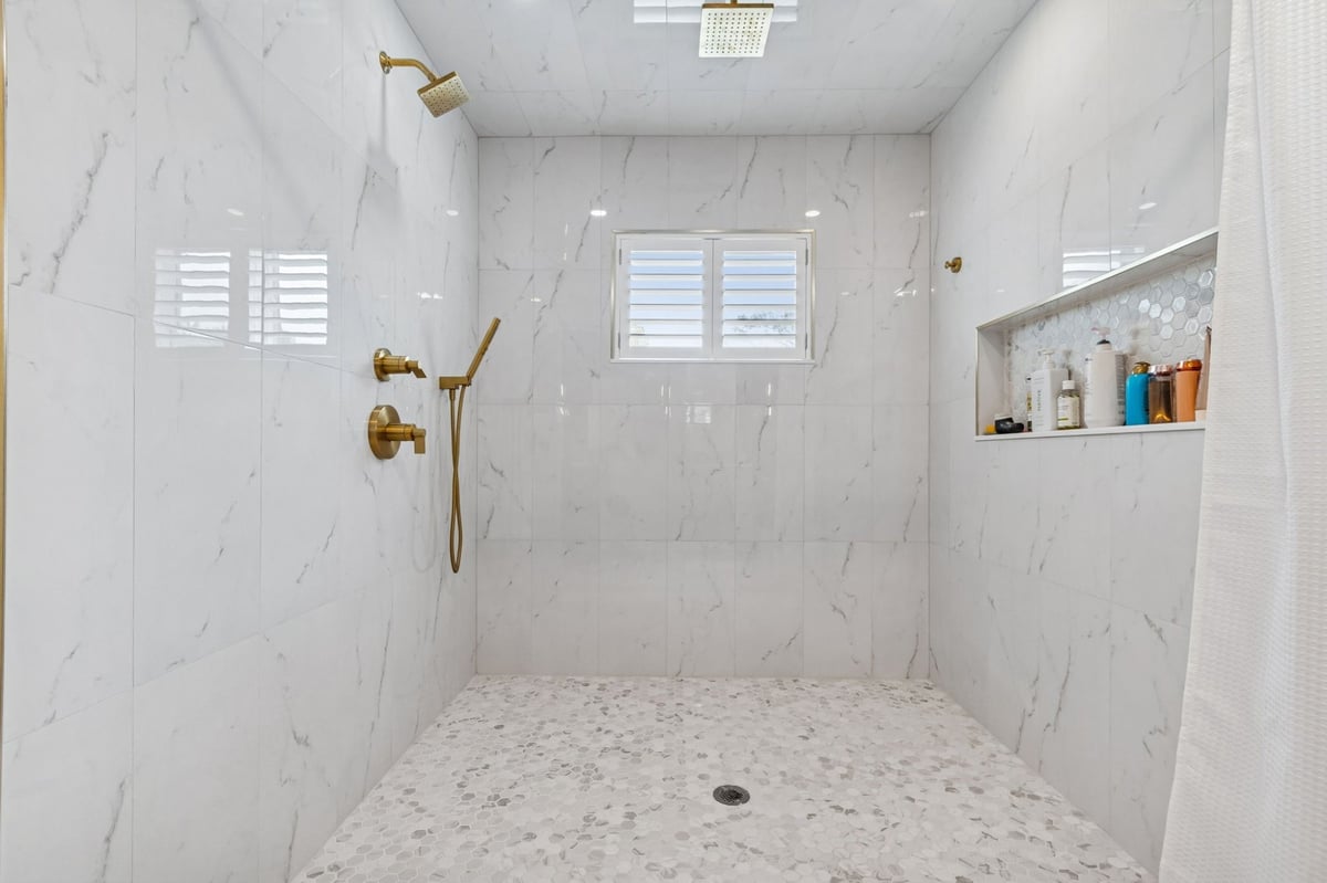 Interior Primary Bath Walk In Shower Marble Tile Gold Fixtures Rain Head
