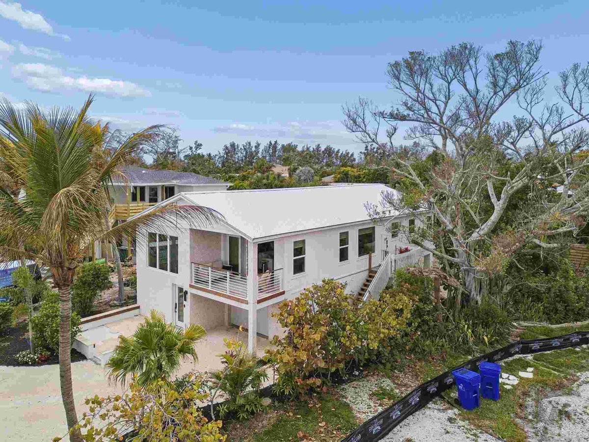 longboat key new home aerial view white metal roof tropical trees