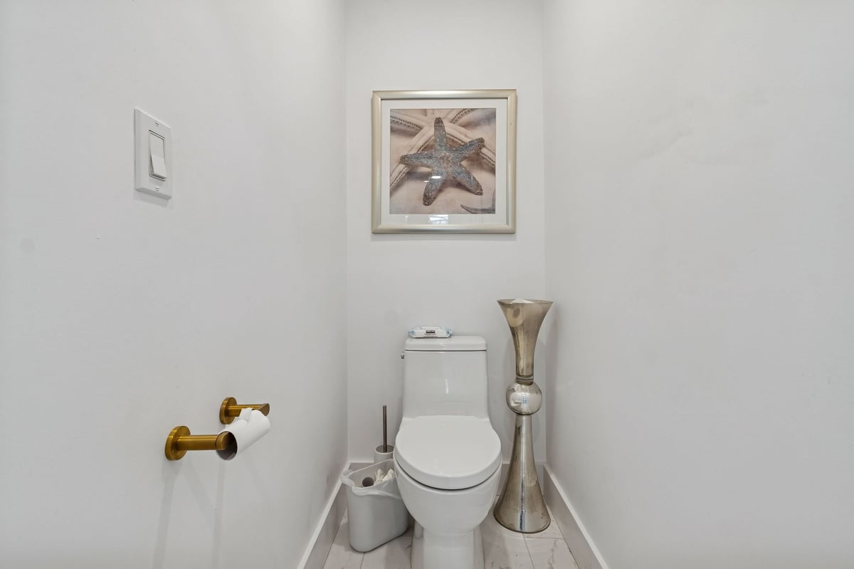 longboat key new home powder room white&nbsp;toilet gold hardware starfish art