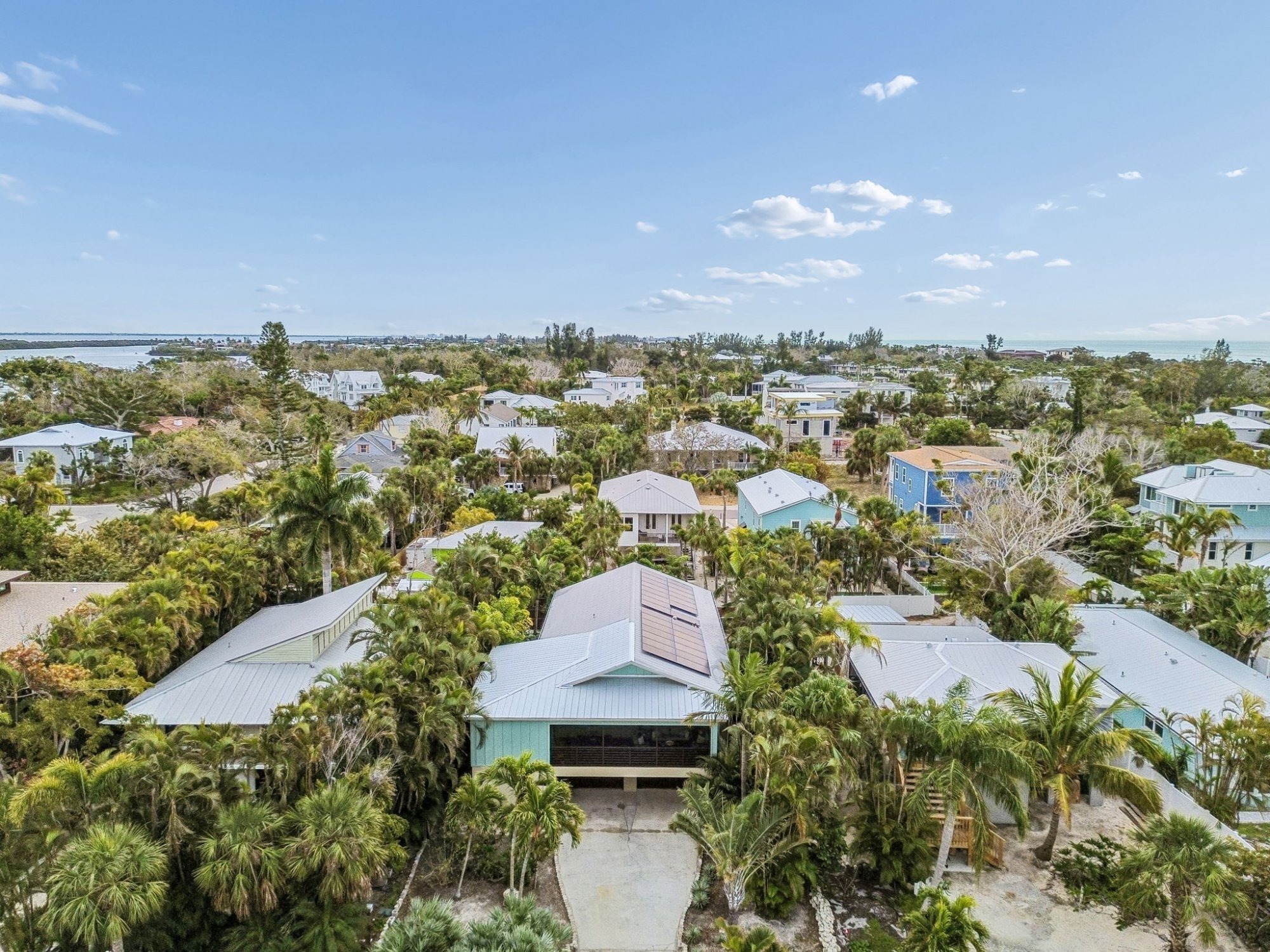 Aerial_Drone_View_Teal_Coastal_Home_Surrounded_By_Palm_Trees_Gulf_Water_Views