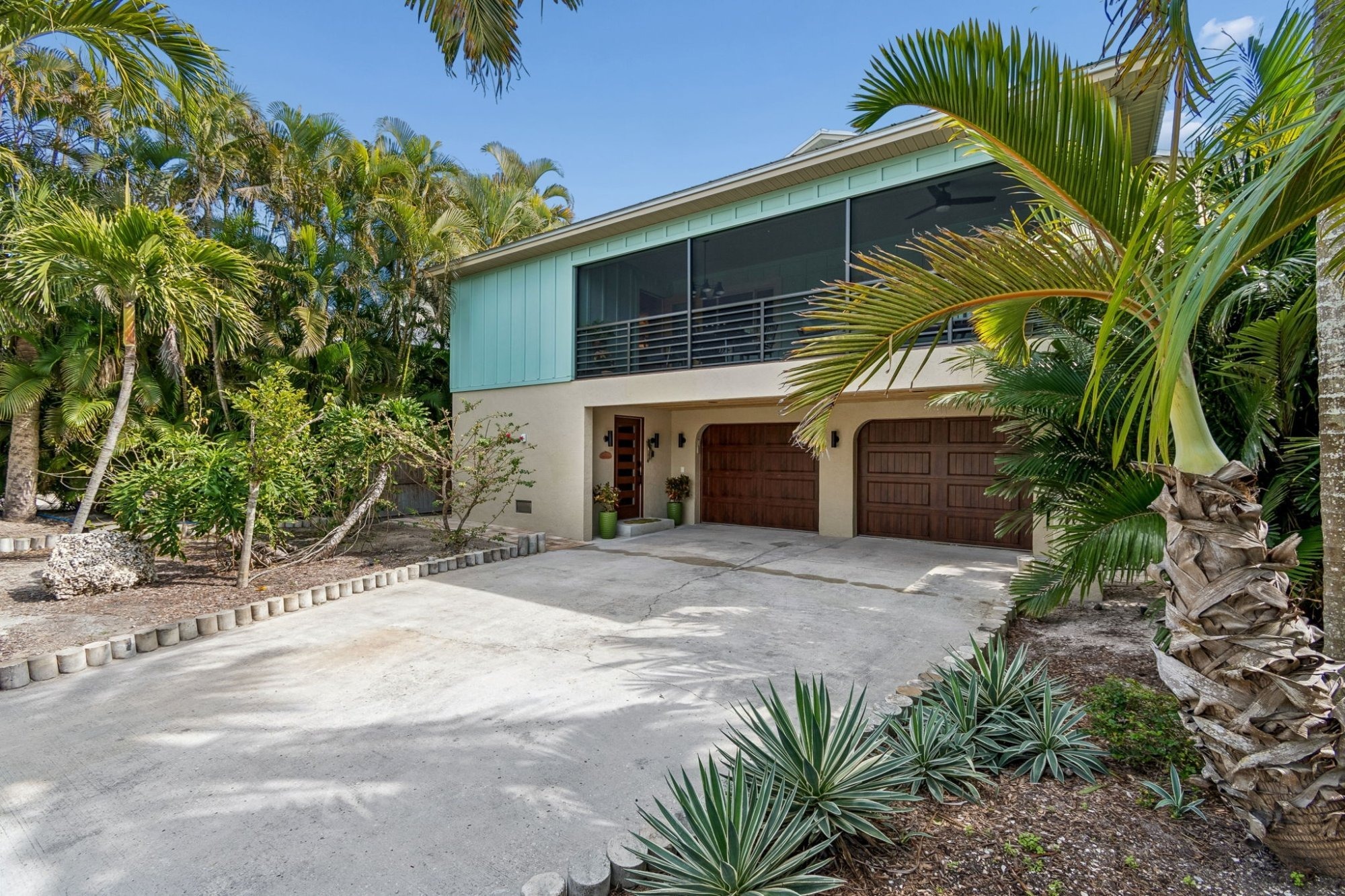 Exterior_Front_Angle_Teal_Home_Wood_Garage_Doors_Tropical_Palms_Agave_Landscaping